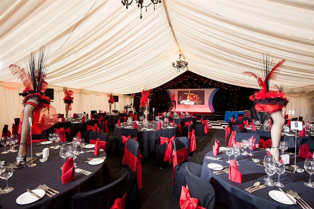 The Grand, York Hotel Exterior photo The photo shows an elegantly decorated event space inside a marquee. The interior features black tables adorned with red napkins and chair sashes, creating a striking contrast. Each table is set with white plates and glassware. The decor includes tal