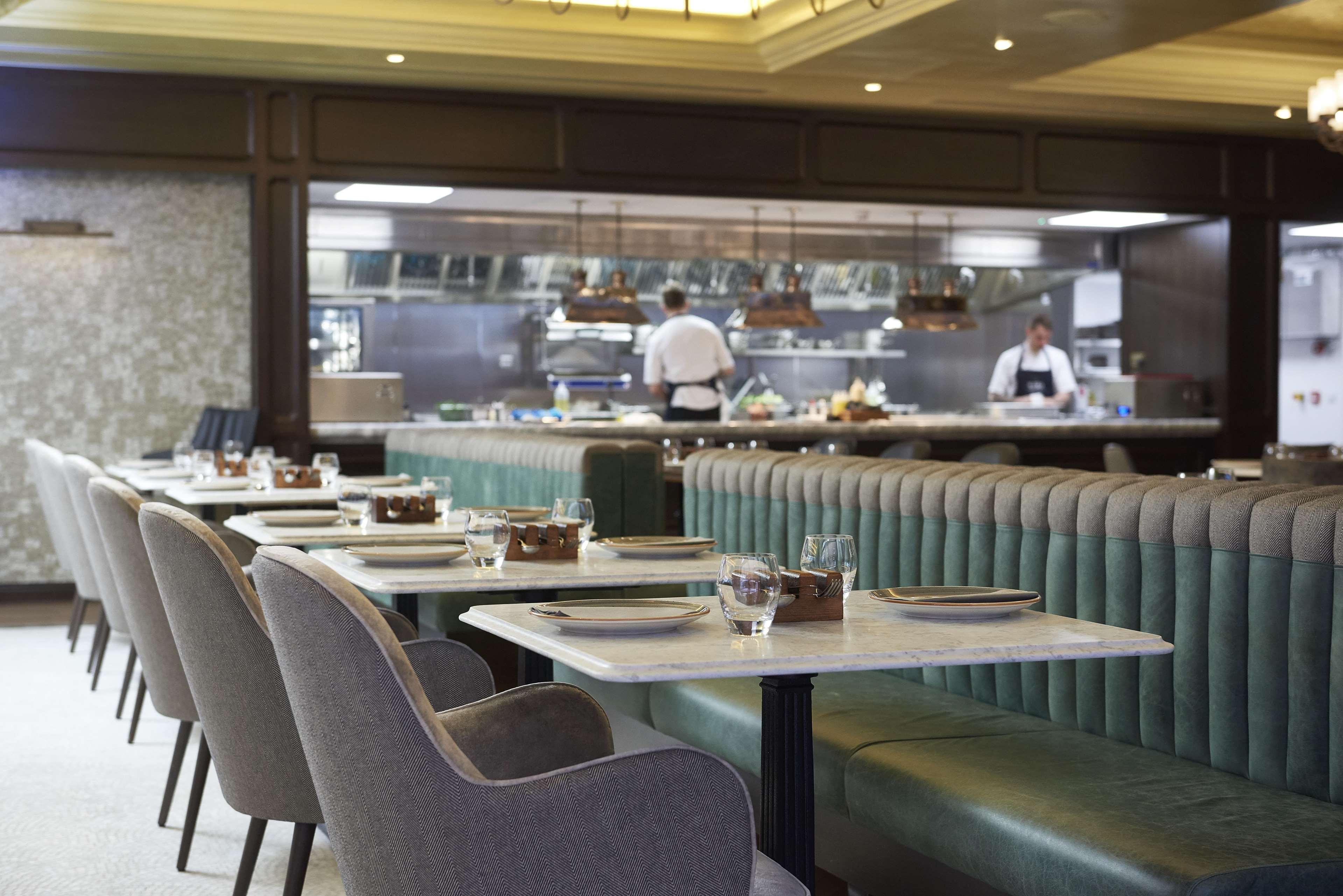 The Grand, York Hotel Exterior photo The photo depicts a modern restaurant interior featuring a spacious dining area with several tables arranged neatly. The tables have white surfaces, and some have small glassware on them. The seating includes comfortable chairs with a combination of 